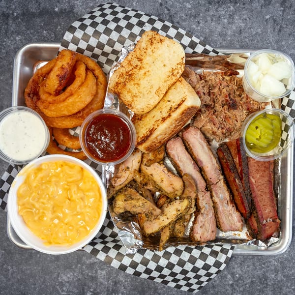 Big Mic's Saloon & BBQ Smokehouse platter with ribs, brisket, pulled pork, chicken, mac and cheese, onion rings, and sauces.