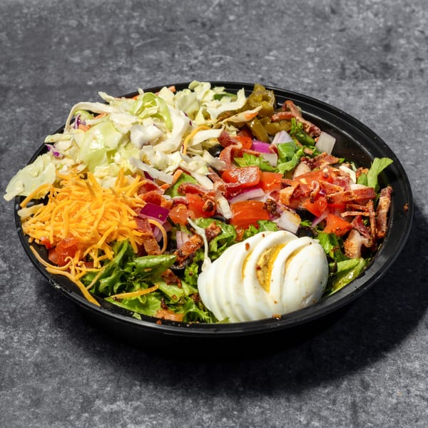Big Mic's Saloon & BBQ Smokehouse salad with coleslaw, cheese, bacon, tomatoes, and hard-boiled egg.