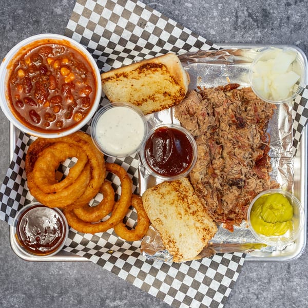 Big Mic's Saloon & BBQ Smokehouse platter with pulled pork, baked beans, onion rings, toast, and sauces.